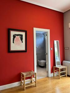 Cette chambre est dotée d'un mur rouge avec une chaise et un miroir. dans l'établissement InStudio Suances, à Suances