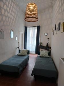 a bedroom with two beds and a chandelier at Le Selamat, Logis XL au calme avec Terrasse in Carcassonne