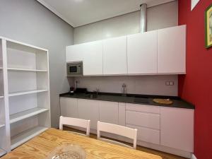 - une cuisine avec des placards blancs, une table et des chaises dans l'établissement InStudio Suances, à Suances