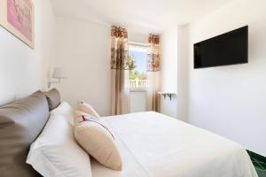 a white bedroom with a bed and a television at Don Leonardo - pool and wellness in Polignano a Mare