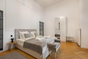 a white bedroom with a large bed and a chair at SUPER CENTRAL 2BR-2BT with Balcony&View&Sauna&Jacuzzi in Budapest