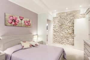 a bedroom with a white bed and a stone wall at B&B CORTE SAN MICHELE Desenzano in San Martino della Battaglia