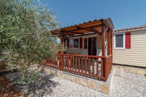 'Olive grove' Camping House-near the beach في Divulje: شرفة منزل مع شرفة خشبية