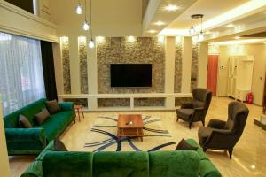 uma sala de estar com um sofá verde e cadeiras e uma televisão em Villa Emre 13 em Sapanca