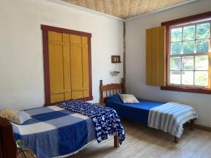 1 dormitorio con 2 camas y 2 ventanas en Sítio Santa Rita, en Prados