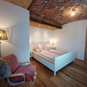 ein Schlafzimmer mit einem großen Bett und einem Stuhl in der Unterkunft Auerhiasbauer in St. Wolfgang