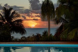 a sunset over the ocean with a swimming pool at Villa Diodon in Deshaies +12 photos