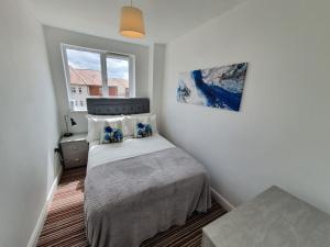 a small bedroom with a bed and a window at Cheerful 4 - Tranquil Oasis Modern and Spacious Retreat 4-Bedroom with Private Parking and Serene Gardens in Luton