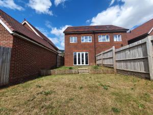 a brick house with a fence in the yard at Cheerful 4 - Tranquil Oasis Modern and Spacious Retreat 4-Bedroom with Private Parking and Serene Gardens in Luton