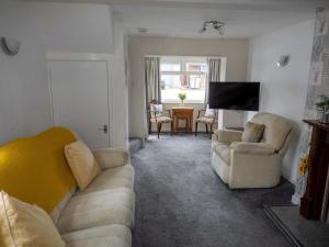 a living room with a couch and chairs and a tv at 8 Heatons Bridge Road in Ormskirk