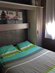 Una cama con almohadas verdes y azules en un dormitorio en Chalet à deux pas de la plage en Martigues