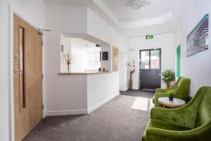 a hallway with two green chairs and a door at Dusties Hotel in Rotherham