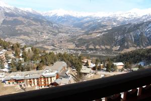 uma vista a partir da varanda de um resort nas montanhas em Praloup 1600 beau studio avec très belle vue em Pra-Loup