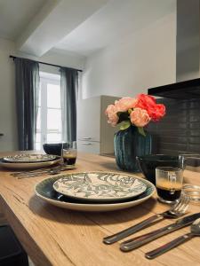 a wooden table with two plates and a vase with flowers at Superbe appartement T2 en plein centre d'Ajaccio, rue Fesch in Ajaccio