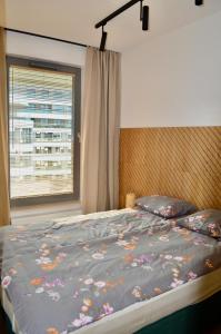 a bedroom with a bed with a floral comforter and a window at Plac Unii Gold Apartment in Gdynia