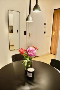 a vase of flowers sitting on a black table at Plac Unii Gold Apartment in Gdynia