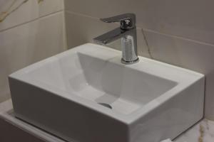 lavabo blanco con grifo en el baño en Hotel Lefkes, en Paralía Skotínis