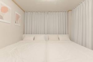 a white bed in a room with white curtains at Koon House in Seoul