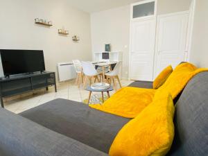 una sala de estar con una manta amarilla en una cama en Esprit Cosy Centre Ville, en Roanne