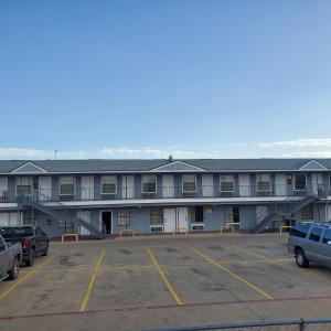 un grand bâtiment avec des voitures garées dans un parking dans l'établissement Motel 9, à Laredo