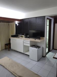 a kitchen with a white counter and a tv at Manos Royal Hotel in João Pessoa