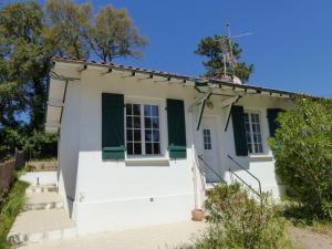 una pequeña casa blanca con persianas verdes en Villa Mitoyenne Pour 4 Personnes Proche Centre-Ville D hossegor, en Hossegor