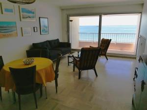 een woonkamer met een tafel en stoelen en een bank bij Le Foch - Appartement face mer avec garage in Les Sables-dʼOlonne