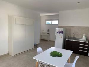 a kitchen with a white table and a white refrigerator at Anandi planta alta in San Nicolás de los Arroyos