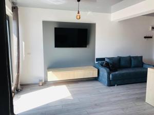 a living room with a blue couch and a tv at DXN Luxury Studio in Năvodari