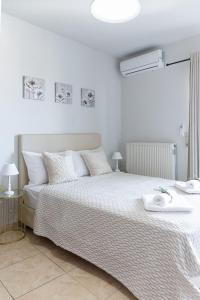 a white bedroom with a large bed with white sheets at Haris apartment 2 in Heraklio