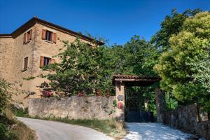 a stone house with a gate and a road at Camera a Casa Castora in Uffogliano