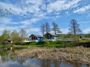 a group of cottages on a hill next to a lake at Osada Pstrąga in Stronie Śląskie