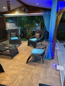 een patio met stoelen en een tafel en blauwe gordijnen bij Balisier in Vieux Bourg