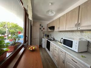 a kitchen with a microwave and a bowl of fruit on a table at Апартамент Иванови in Pomorie