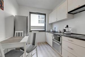 une cuisine avec des placards blancs, une table et un comptoir dans l'établissement Apartament OldNova, à Gdańsk