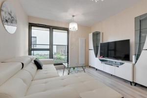 a living room with a white couch and a flat screen tv at Apartament OldNova in Gdańsk