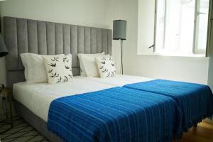 een slaapkamer met een groot bed met een blauwe deken bij Vila Intendente - Apartamento 2 Quartos in Lissabon +9 foto's