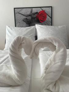 Una cama con toallas blancas y una rosa en Apartament Regina, en Ustka