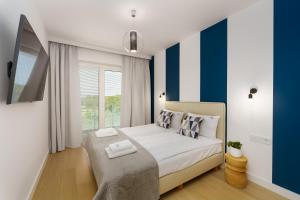 sypialnia z łóżkiem z niebieskimi i białymi paskami w obiekcie Klif Apartamenty Polanki Aqua A414 w Kołobrzegu +28 zdjęć