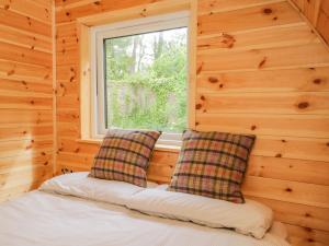 a bed in a wooden room with a window at Pod 1 in Seascale