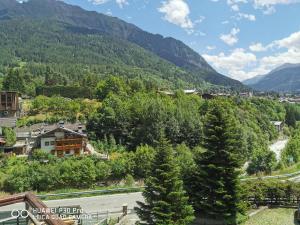 Affascinante appartamento ai piedi dell'ovovia في كورمايور: مدينه في جبال فيها طريق واشجار