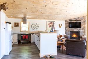 een keuken en een woonkamer met houten plafonds en een open haard bij Woodhaven - Seaside Accommodations in Waweig