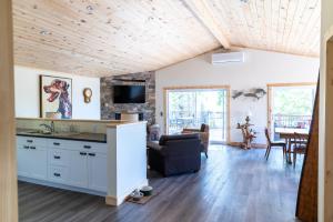 a kitchen and living room with a wooden ceiling at Woodhaven - Seaside Accommodations in Waweig