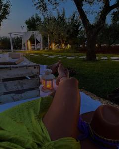 a woman laying on a blanket in a park with her feet up at Aria di Casa Country Resort in Alberobello