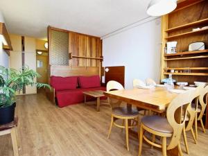 Studio Chamrousse, 1 pièce, 4 personnes - FR-1-549-33 في شامروس: غرفة طعام مع طاولة وأريكة حمراء