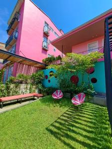 a pink building with pink umbrellas in the grass at Rossa Palma in Cali