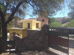 een geel huis achter een hek met een hek bij Casa boutique en cuesta blanca in Villa Icho Cruz