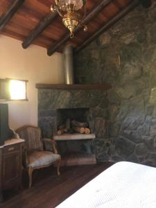 een stenen open haard in een slaapkamer met een stoel bij Casa boutique en cuesta blanca in Villa Icho Cruz