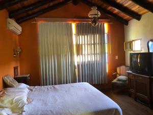 een slaapkamer met een bed, een tv en een raam bij Casa boutique en cuesta blanca in Villa Icho Cruz