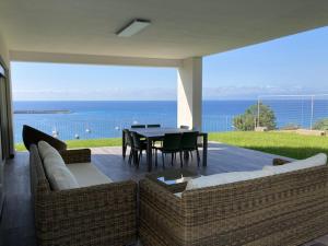 een patio met 2 banken en een tafel met uitzicht op de oceaan bij Residenza Timpa Janca in Vibo Valentia Marina